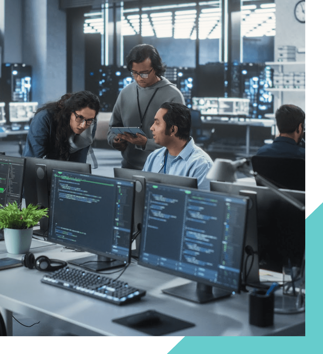 Office team discussing code on computer screens.