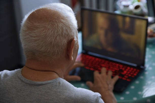 Senior man at home using laptop for video conference